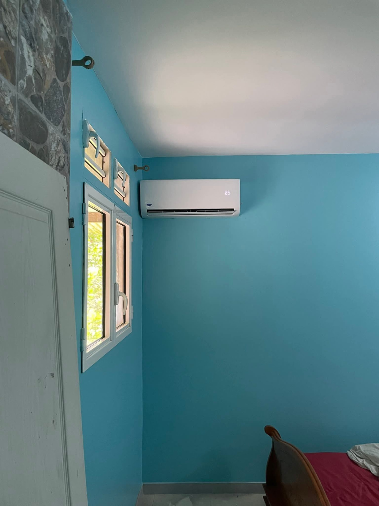 Remplacement 9k BTU – Le Gros-Morne – climatisation Martinique Remplacement d'un climatiseur 9 000 BTU au Gros-Morne : nouvelle unité murale blanche fixée en hauteur dans une chambre aux murs turquoise – Le Gros-Morne, Martinique – LD CLIM 972