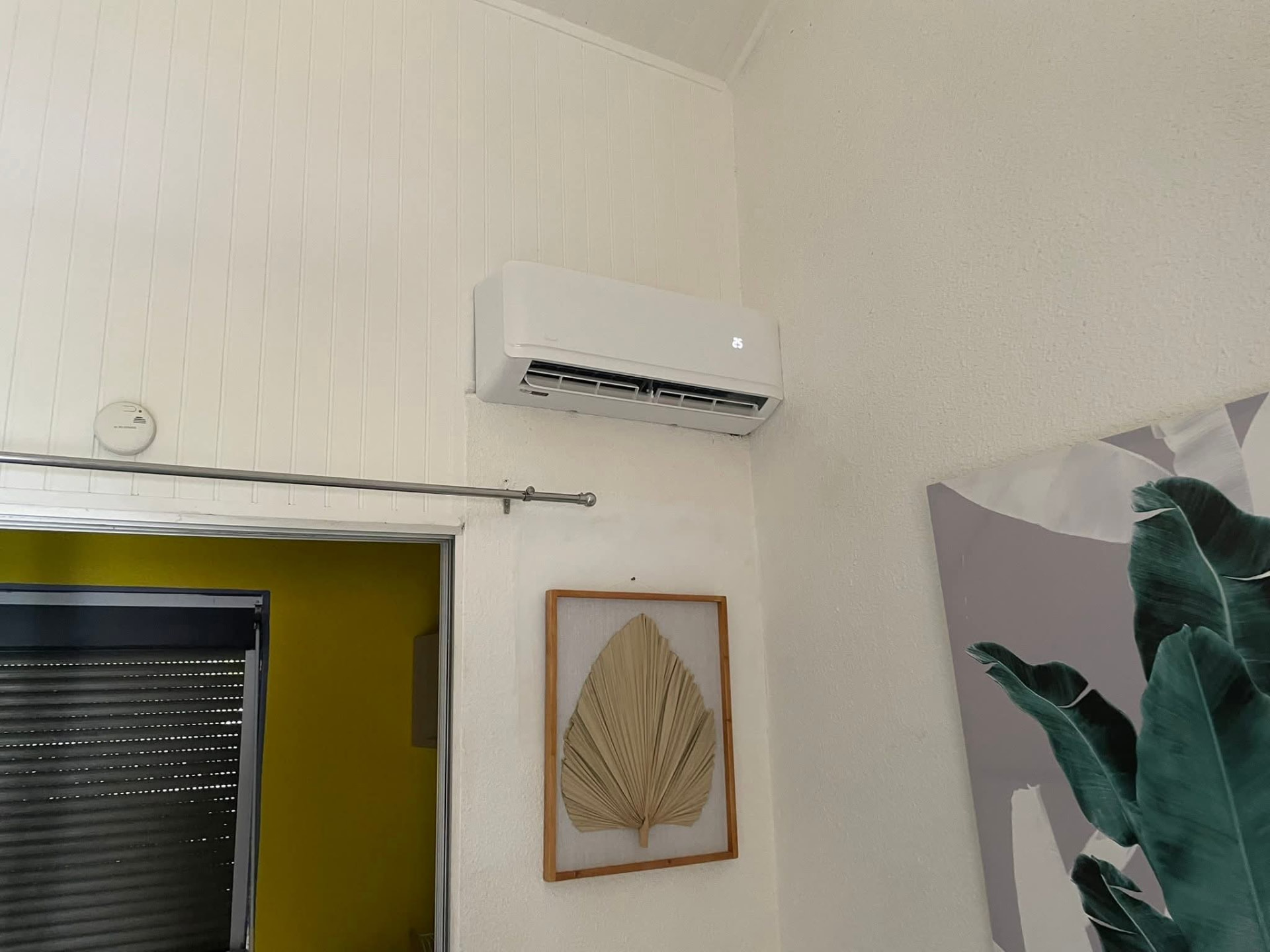 Remplacement 9k BTU – Le Gros-Morne – climatisation Martinique Unité extérieure Airwell fixée sur la façade d'une maison au Gros-Morne, feuilles de bananier au premier plan, après remplacement d'un climatiseur 9 000 BTU – Le Gros-Morne, Martinique – LD CLIM 972
