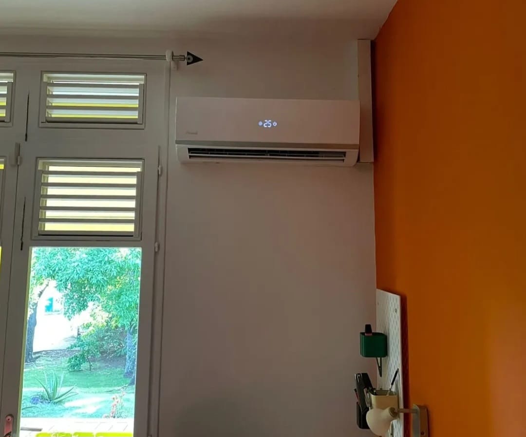 Unité intérieure murale Airwell – climatisation Martinique Climatiseur mural Airwell installé près d'une fenêtre à persiennes, solution de climatisation adaptée à l'habitat martiniquais, Martinique – LD CLIM 972