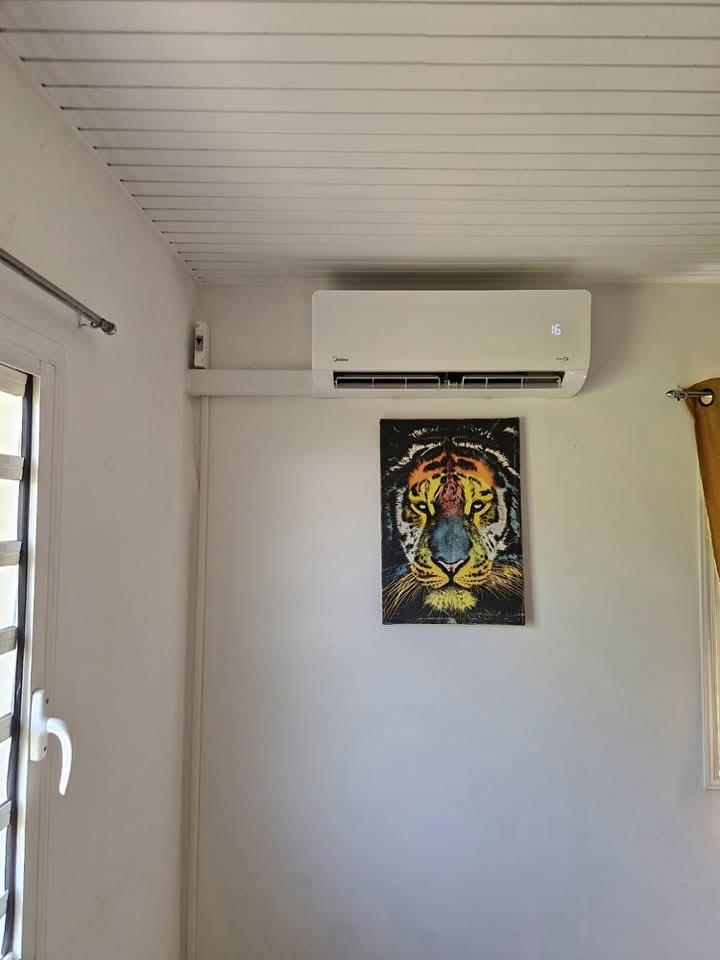 Installation Midea 9 000 BTU à Ducos : climatiseur mural fixé en partie haute d'un mur blanc, raccordé proprement par goulotte à un boîtier électrique – Ducos, Martinique – LD CLIM 972