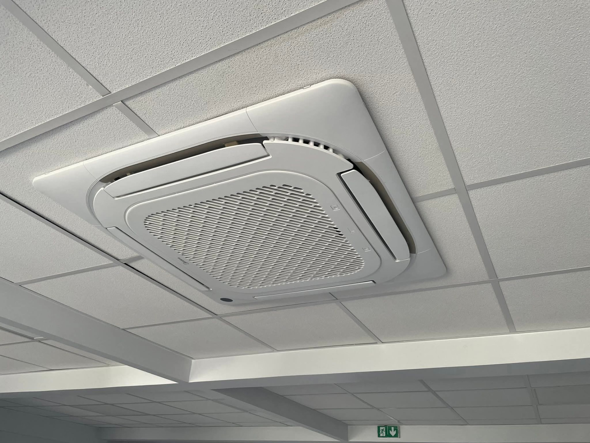 Cassette de plafond Midea intégrée à un faux-plafond à ossature apparente dans des locaux professionnels du Lamentin, panneau d'évacuation en partie basse – Lamentin, Martinique – LD CLIM 972